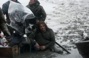 Gerard Butler and camera crew sitting in mud